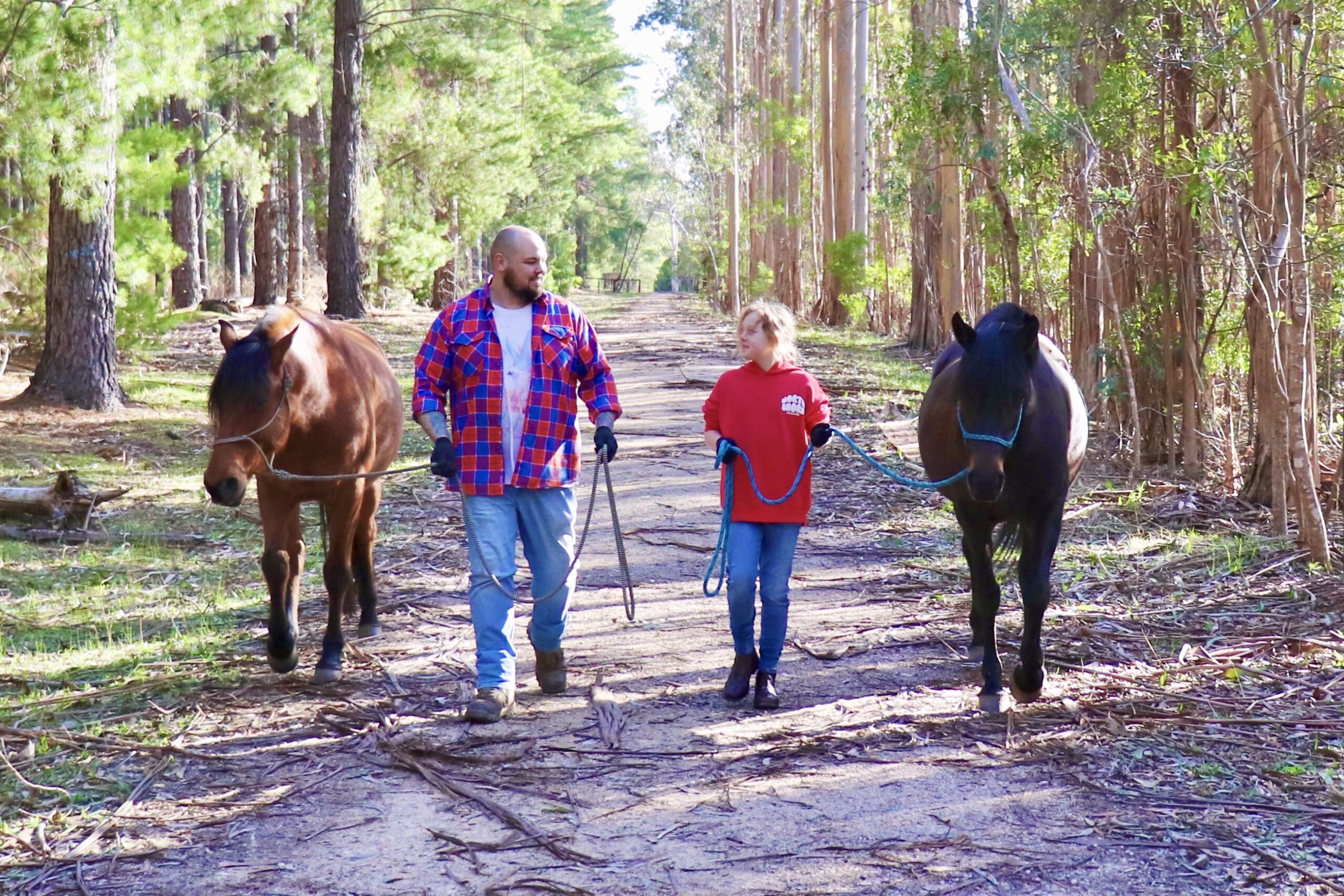 Father and daughter walking with horses